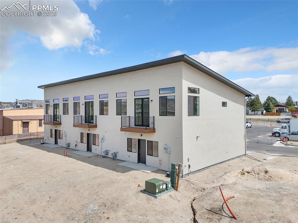 Rear view of property featuring fence, a balcony, and stucco siding