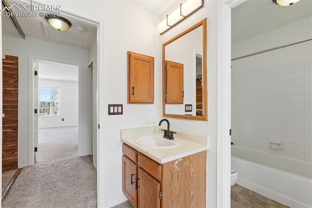 Bathroom with vanity, bathtub / shower combination, and light colored carpet