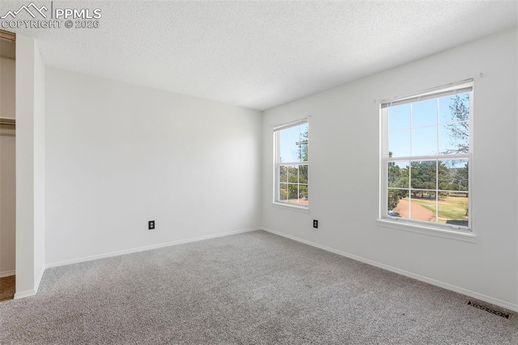 Empty room featuring a textured ceiling and carpet floors