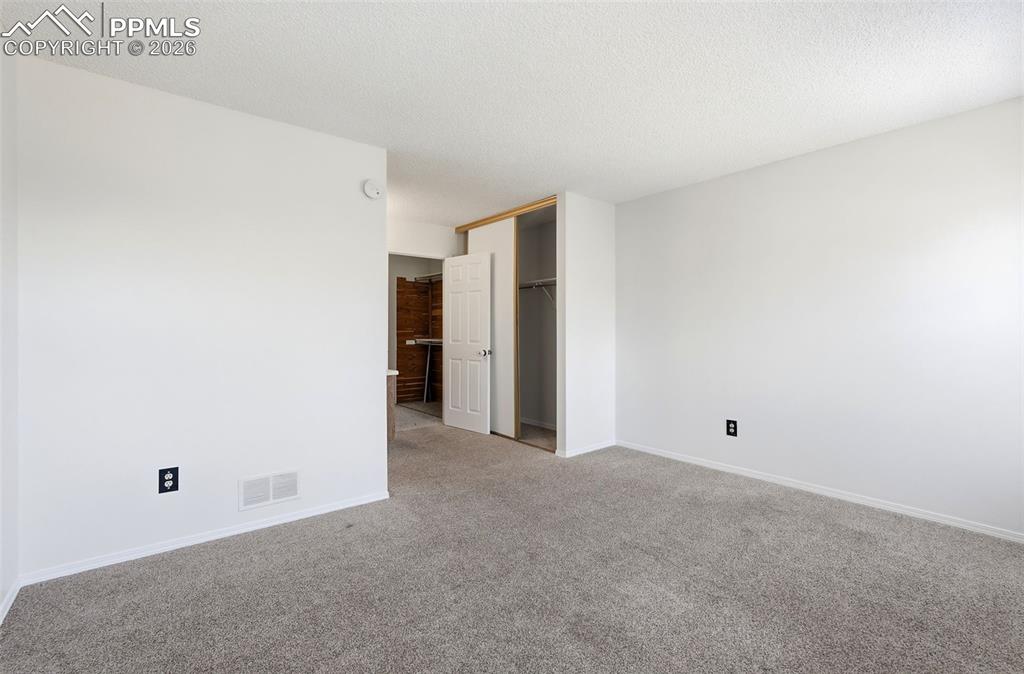 Unfurnished bedroom with carpet flooring, a textured ceiling, and a closet