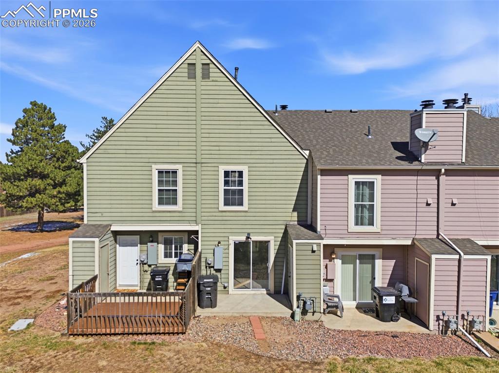 Back of house with a storage shed, a patio area, and a shingled roof