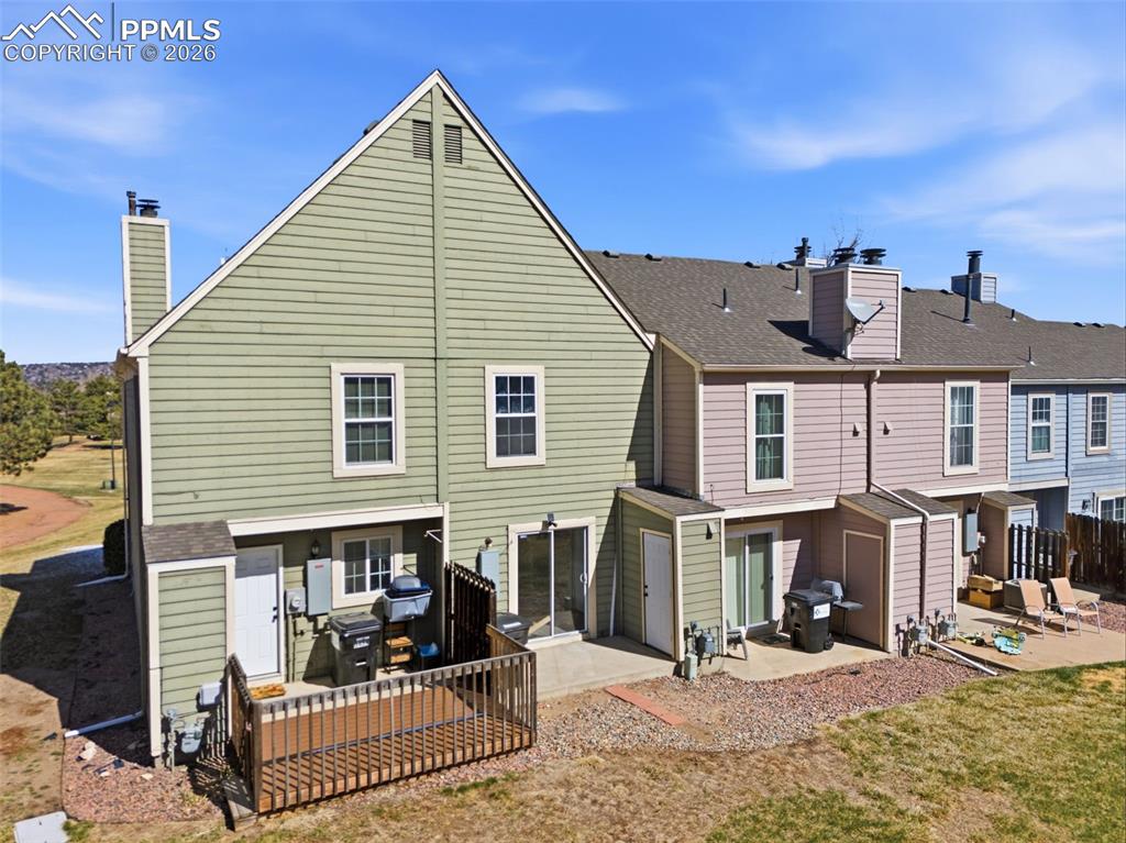 Back of house with a patio area, a chimney, a shingled roof, and a residential view