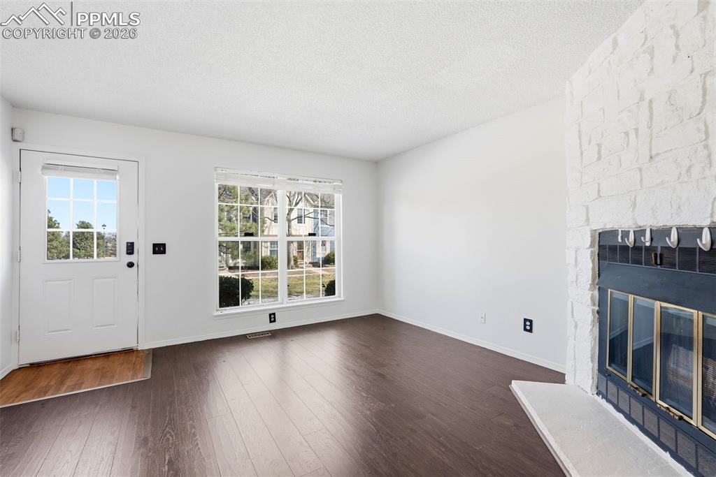 Unfurnished living room with dark wood-type flooring, a fireplace, and a textured ceiling