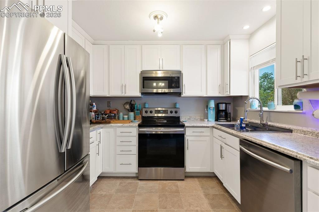 Kitchen with stainless steel appliances, white cabinetry, and recessed lighting