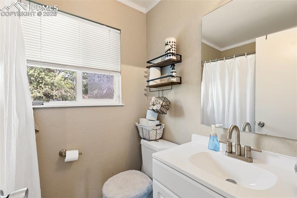 Full bathroom with vanity, ornamental molding, and a textured wall
