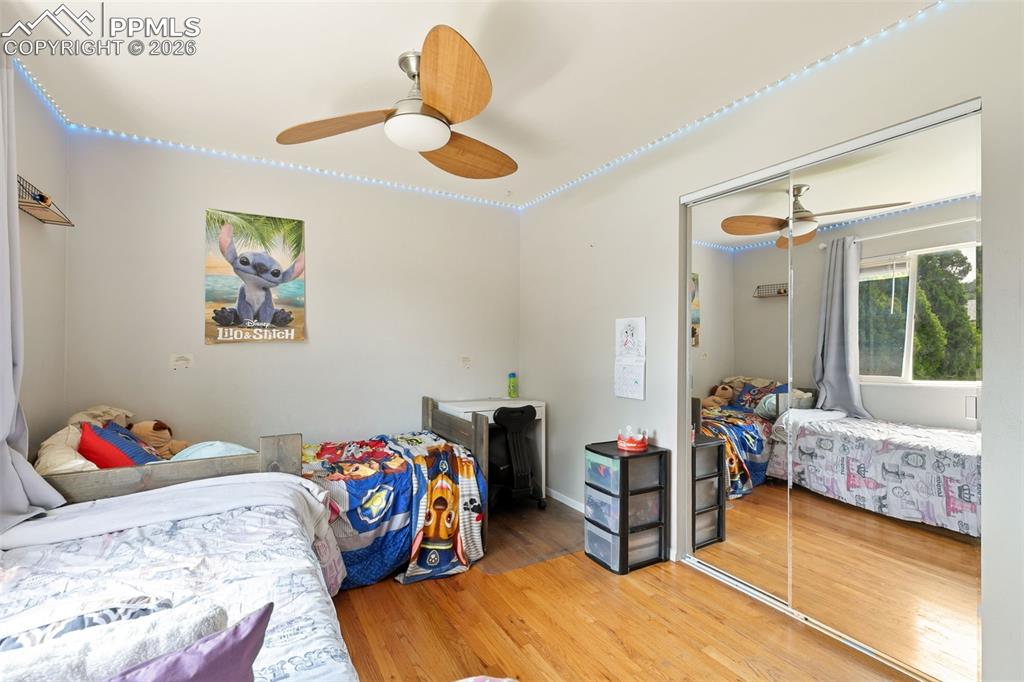 Bedroom with wood finished floors, a closet, and ceiling fan