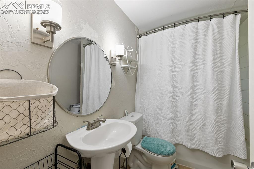 Full bathroom featuring a textured wall and shower / bath combination with curtain