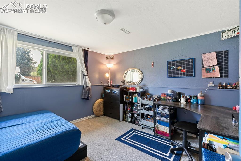 Carpeted bedroom featuring ornamental molding and a desk