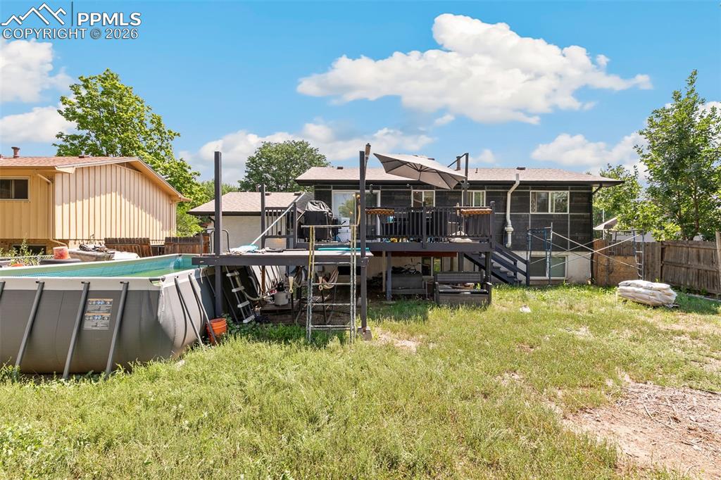 Back of property featuring a deck, a fenced backyard, and stairs
