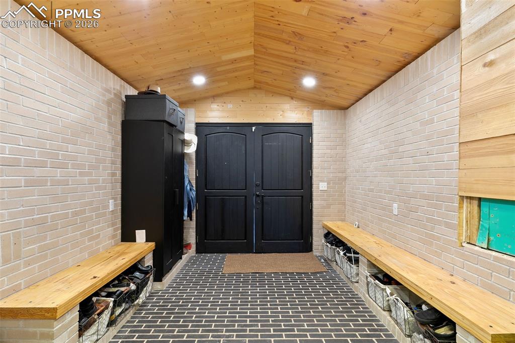 Mudroom with brick wall, wood ceiling, brick flooring, vaulted ceiling, and recessed lighting