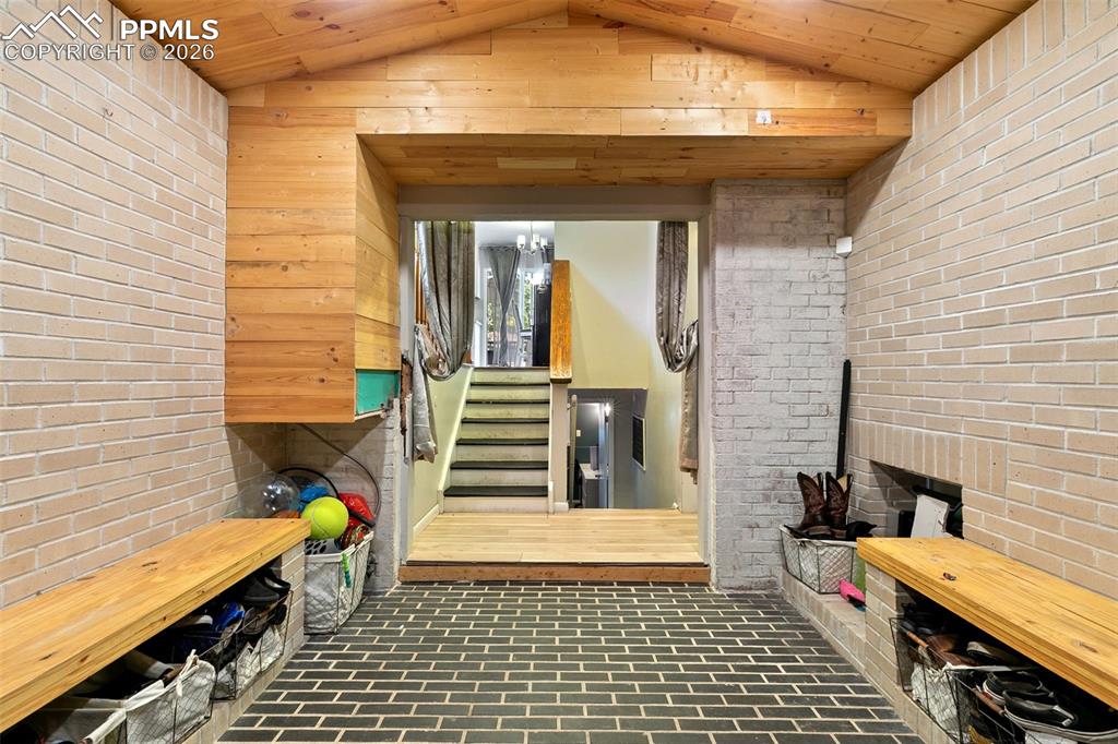 Mudroom featuring brick wall, brick floors, vaulted ceiling, wood ceiling, and a sauna