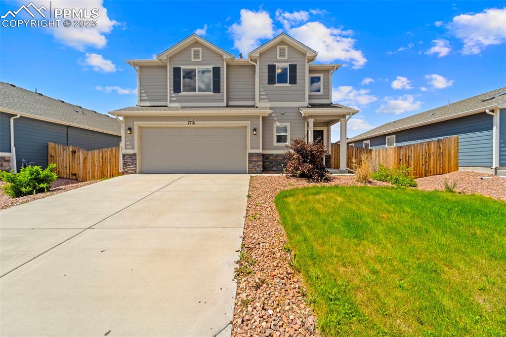 View of front of property with an attached garage, concrete driveway, and stone siding