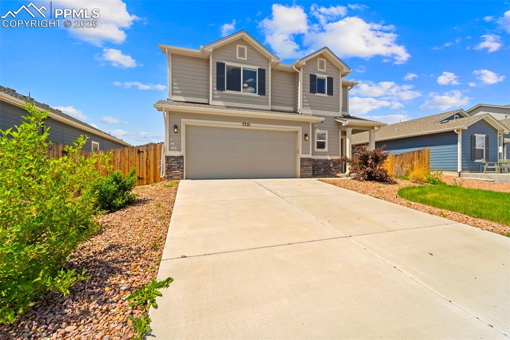 View of front of home featuring a garage, stone siding, and driveway