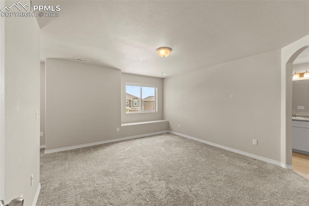 Empty room featuring arched walkways and light carpet