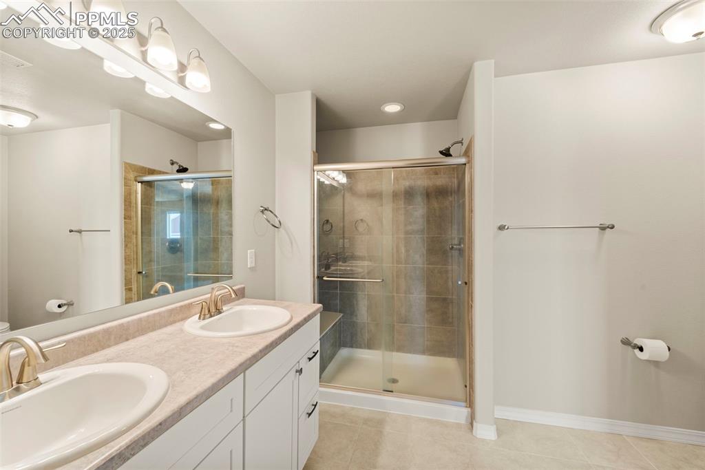Full bathroom featuring tile patterned floors, a stall shower, double vanity, and recessed lighting