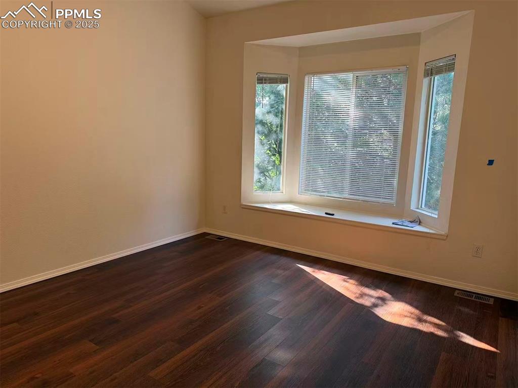 Empty room with baseboards and dark wood-type flooring
