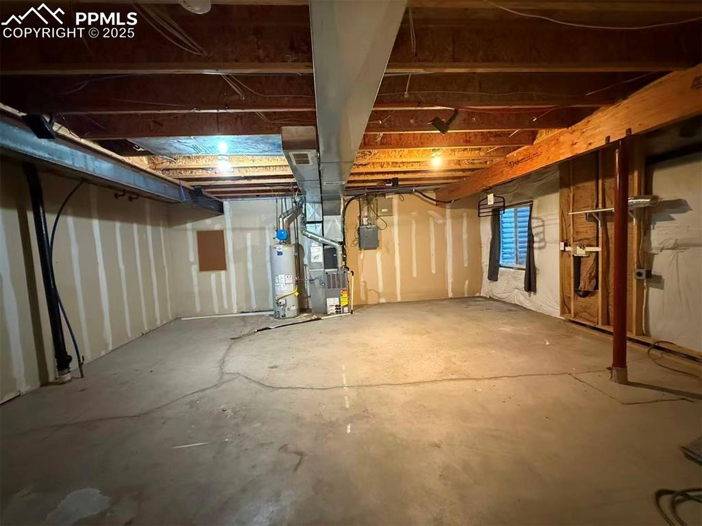 Unfinished basement featuring heating unit and water heater
