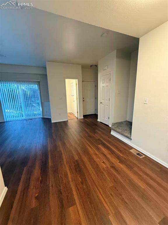 Unfurnished living room with dark wood-type flooring