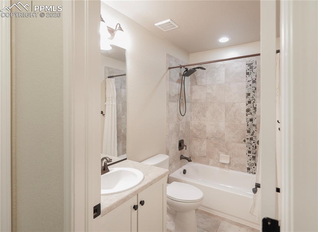 Full bathroom with vanity, shower / tub combo with curtain, and light tile patterned flooring