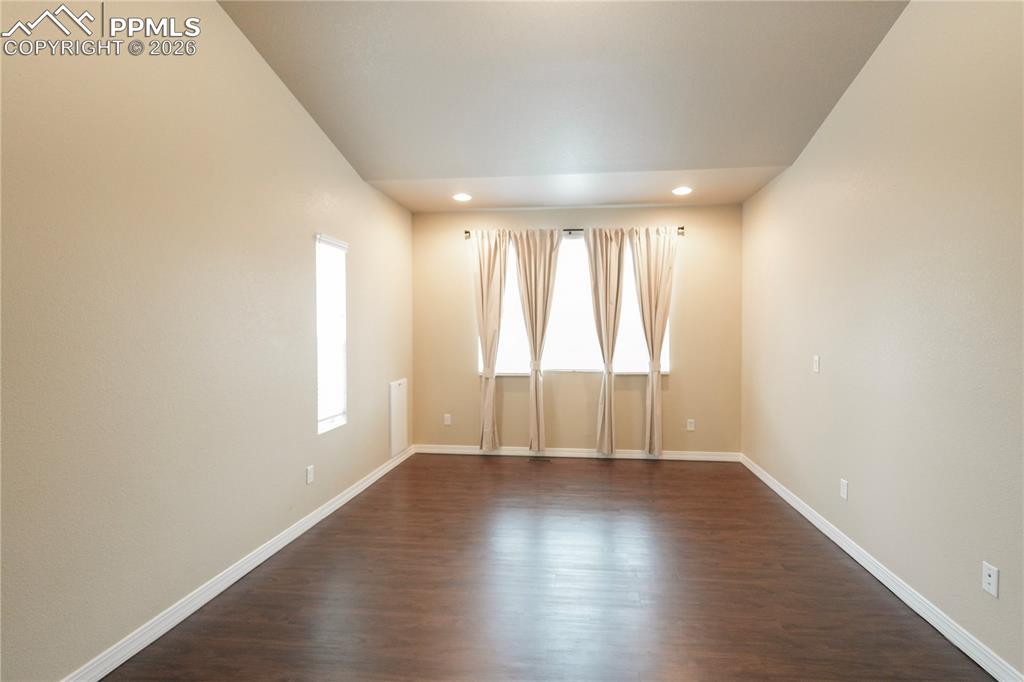 Empty room with dark wood-style floors and recessed lighting