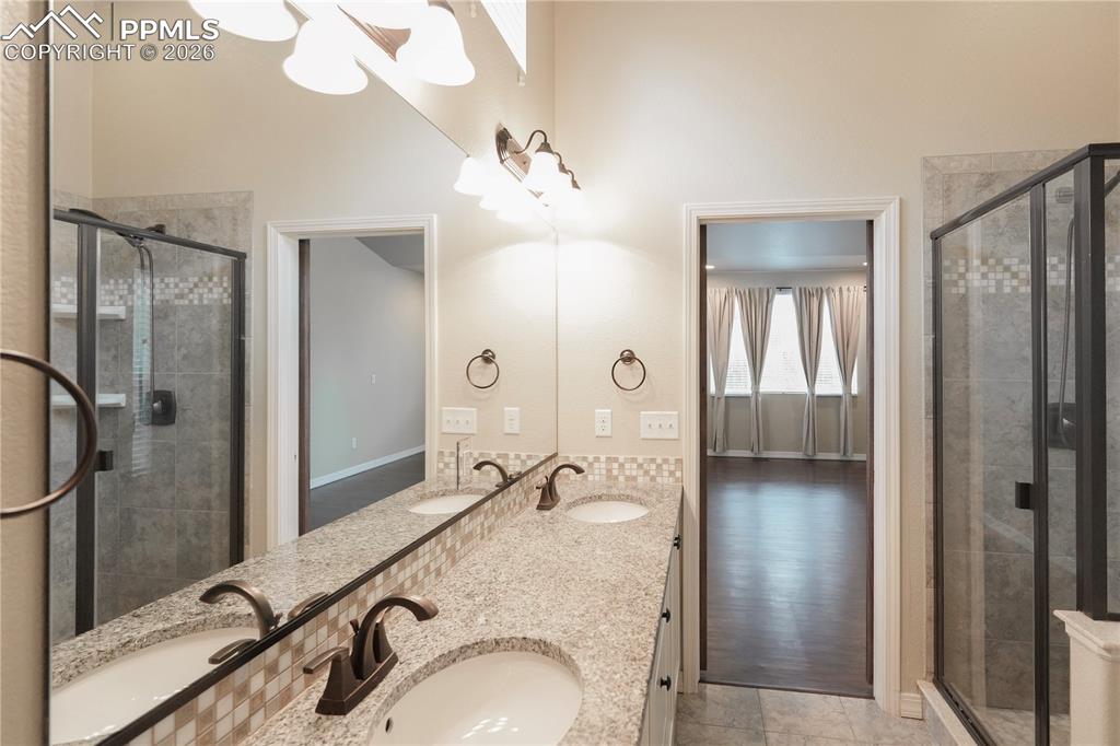 Full bath featuring double vanity and a shower stall
