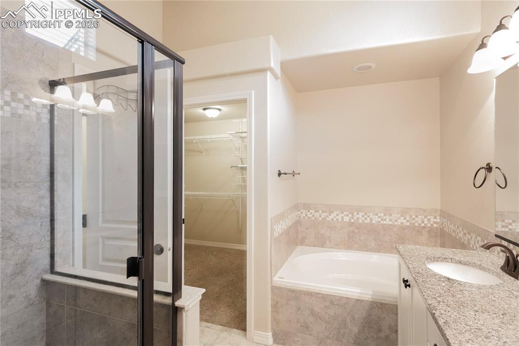 Full bath with vanity, a spacious closet, a bath, and a shower stall
