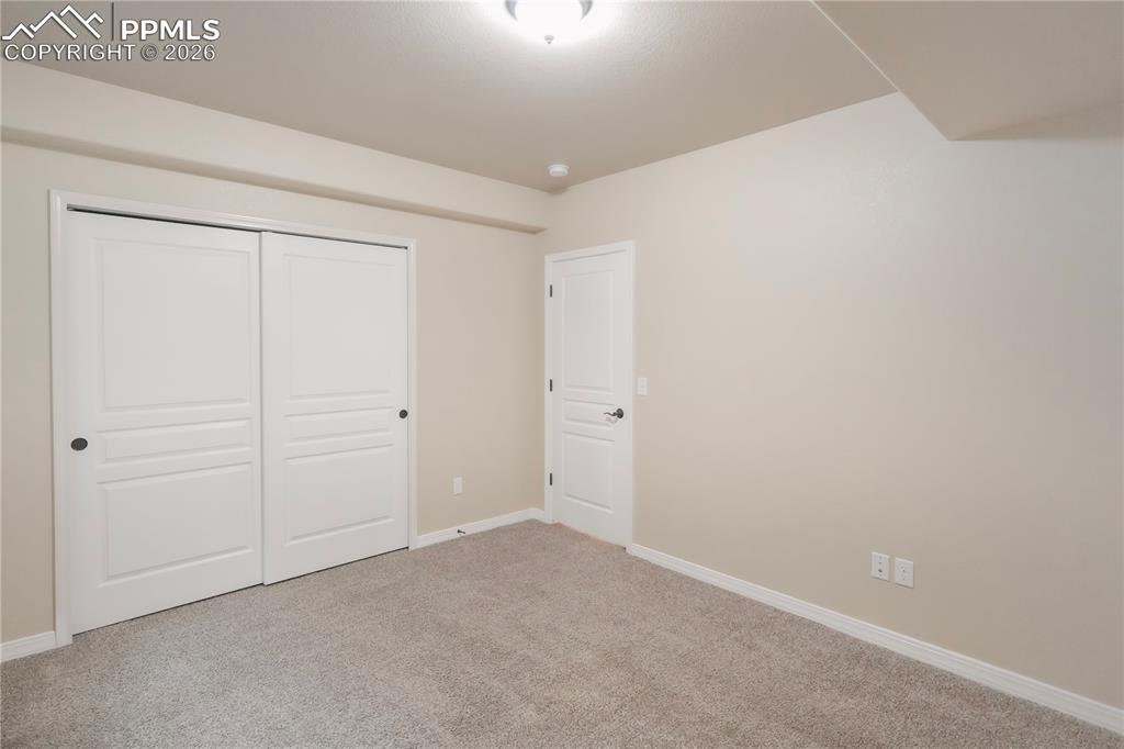 Unfurnished bedroom with light colored carpet and a closet