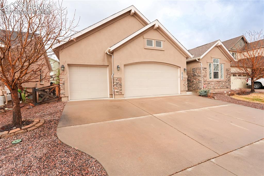 View of front facade with stucco siding, concrete driveway, a garage, and stone siding