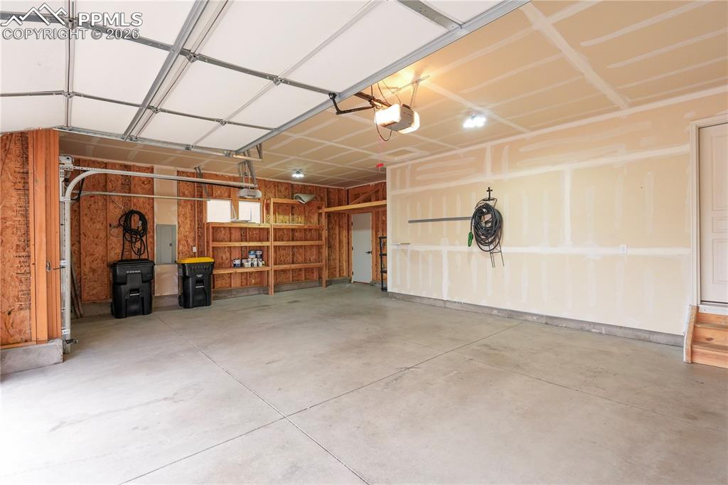 Garage featuring electric panel and a garage door opener