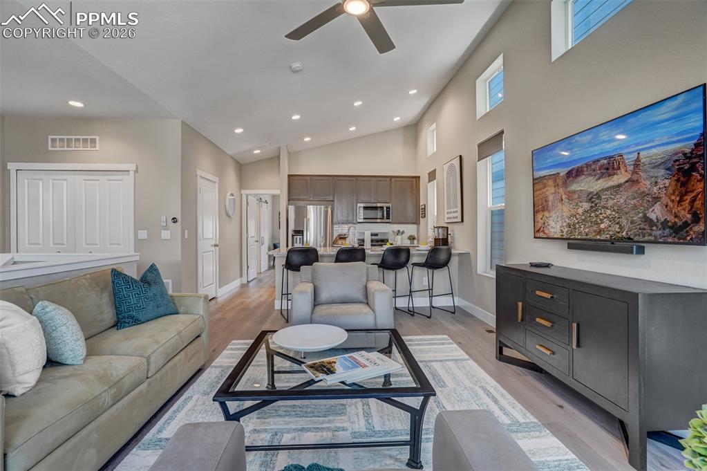 Living room featuring a ceiling fan, light wood-style floors, recessed lighting, and vaulted ceiling