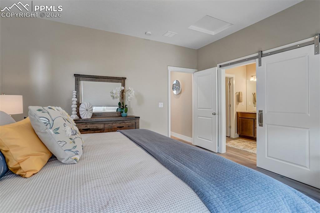 Bedroom featuring a barn door, wood finished floors, and ensuite bathroom
