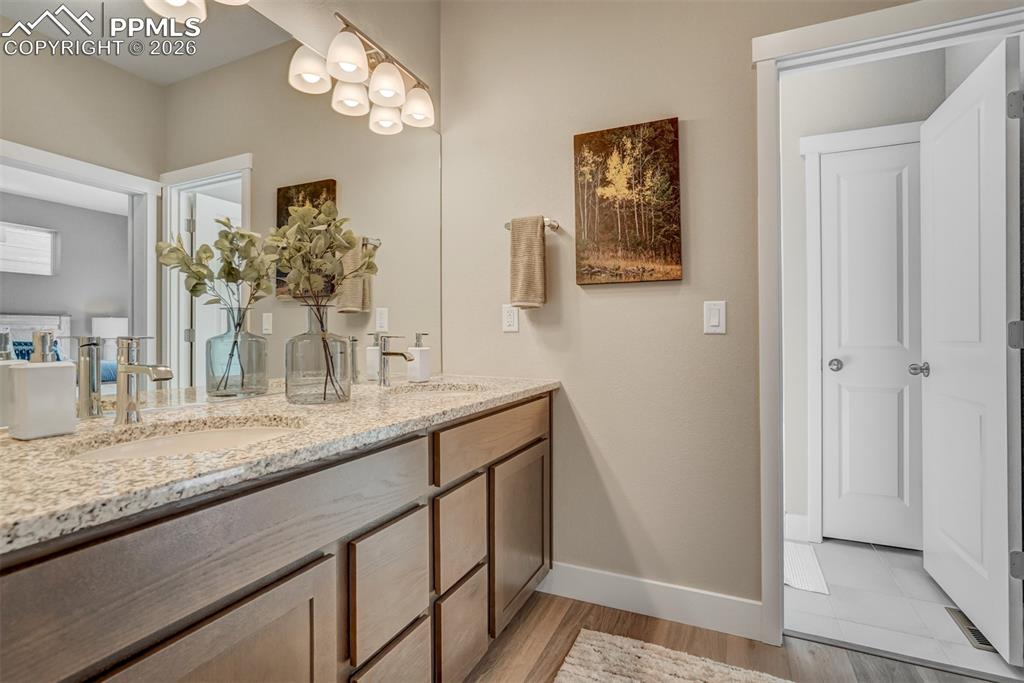 Full bathroom featuring double vanity and light wood finished floors