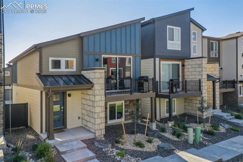Contemporary home featuring stone siding and a standing seam roof