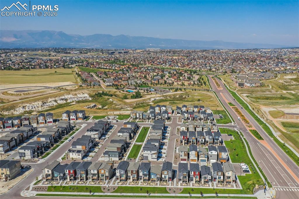 Aerial perspective of suburban area featuring a mountain backdrop and a local golf course