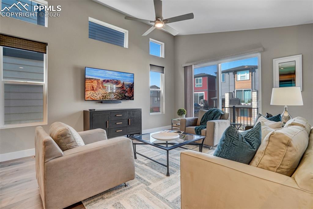 Living room featuring a ceiling fan, wood finished floors, and lofted ceiling