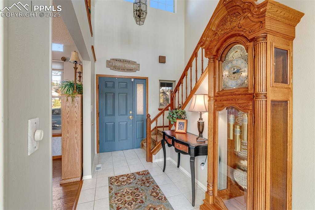 Entrance foyer featuring healthy amount of natural light, stairway, light tile patterned floors, and a high ceiling