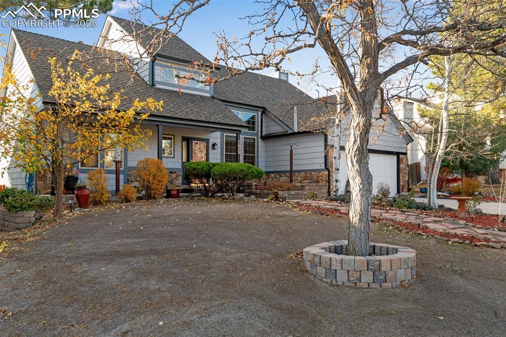 View of front of home featuring a shingled roof, covered porch, an attached garage, and driveway