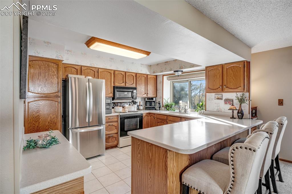 Kitchen with a peninsula, oak cabinetry, solid surface countertops, tile flooring, and mountain views from the sink.