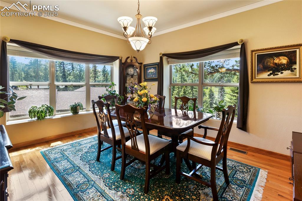 The dining area features decorative molding, light-colored wood-style flooring, and a chandelier.