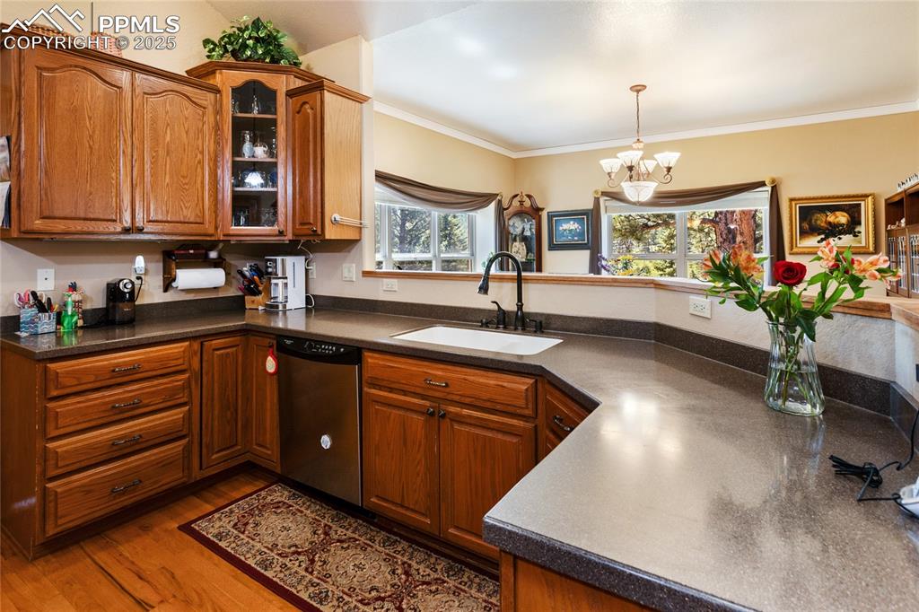 Kitchen with dark countertops, glass insert cabinets, stainless steel dishwasher, wooden cabinetry, overlooking the dining room.