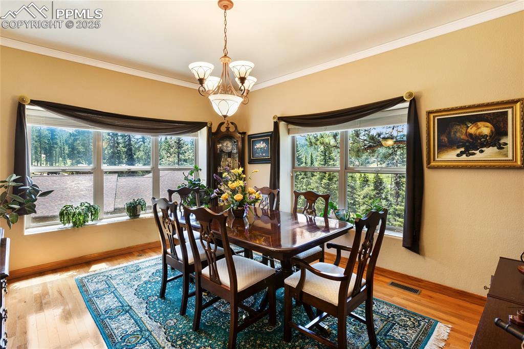 Dining area featuring crown molding, light wood floors, and a chandelier.