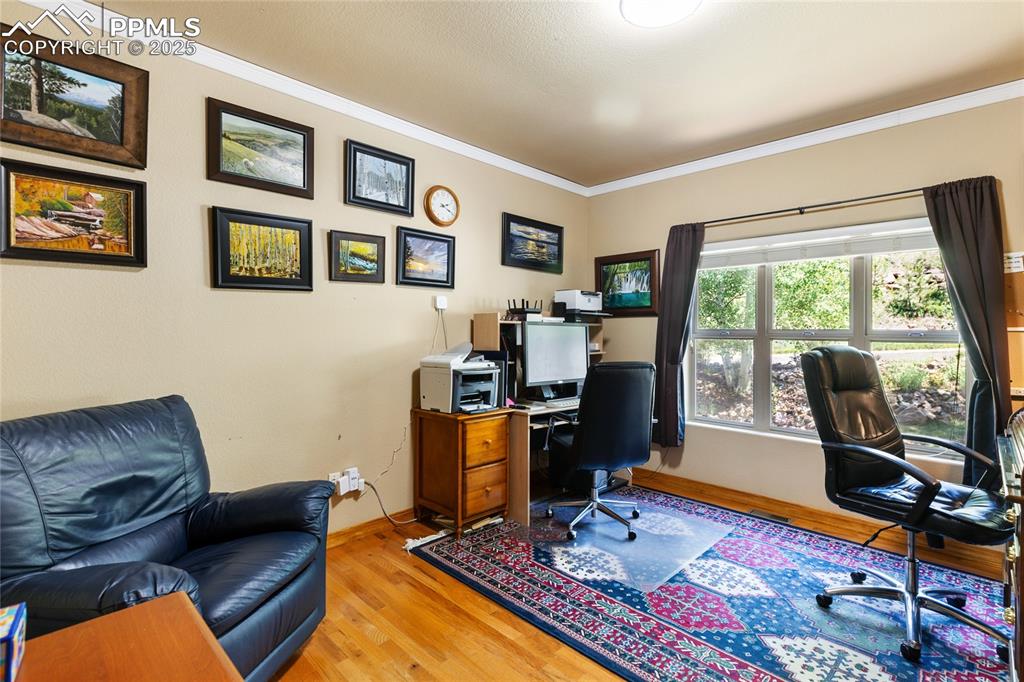 Office space featuring light wood-style flooring and crown molding.