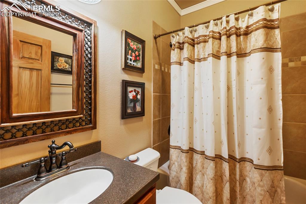 Bathroom with shower / bath combo, vanity, and crown molding.