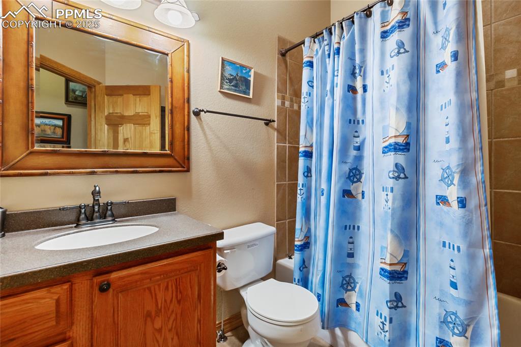 Bathroom with vanity, shower / bath combo with shower curtain.