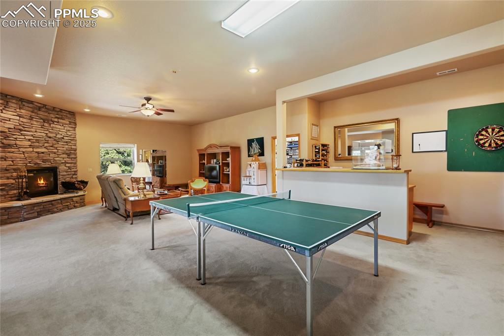 The rec room features carpet floors, a ceiling fan, recessed lighting, and a fireplace. 