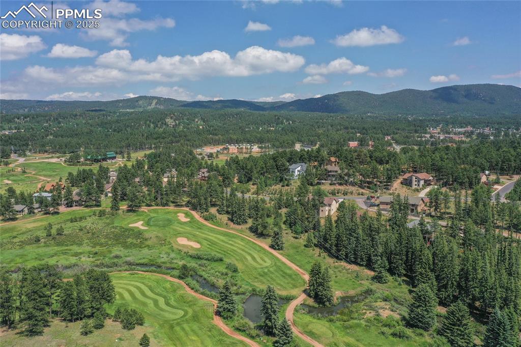 Aerial overview of property's location with a mountain backdrop and a golf course. 