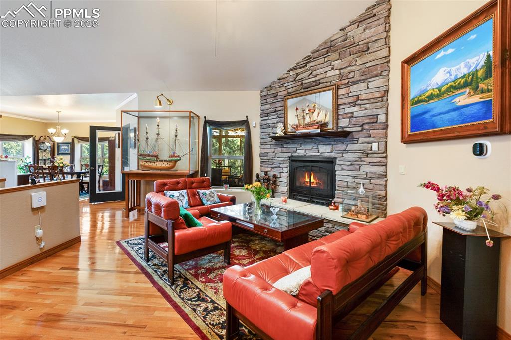 Living room with light wood-style floors, lofted ceiling, and a gas fireplace. 