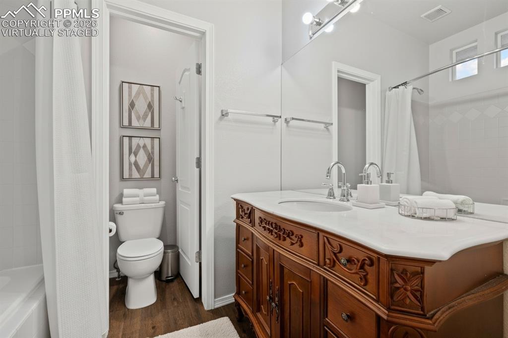 Full bath with a bathtub, wood-like floor. This photo is virtually staged.
