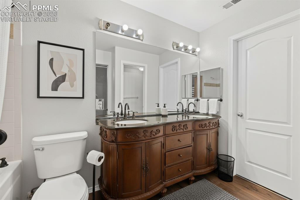 Full bath with double vanity, shower / bathtub combination with curtain, and wood finished floors. This photo is virtually staged.