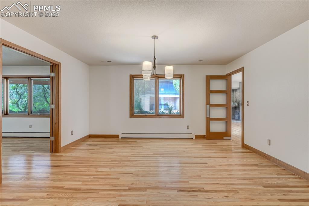 Unfurnished dining area with a chandelier, light wood-style floors, and baseboard heating